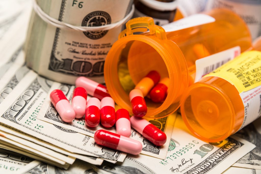 Bottle of pills spilling on a pile of $100 bills