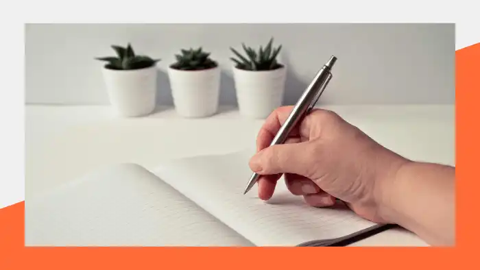 Person holding a pen and writing in a notebook