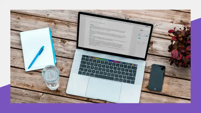 Document open on a laptop, next to a notebook glass and smartphone