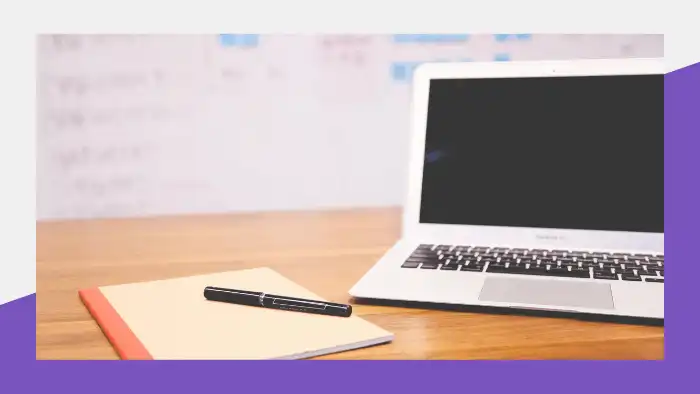 Pen and notebook next to an open laptop