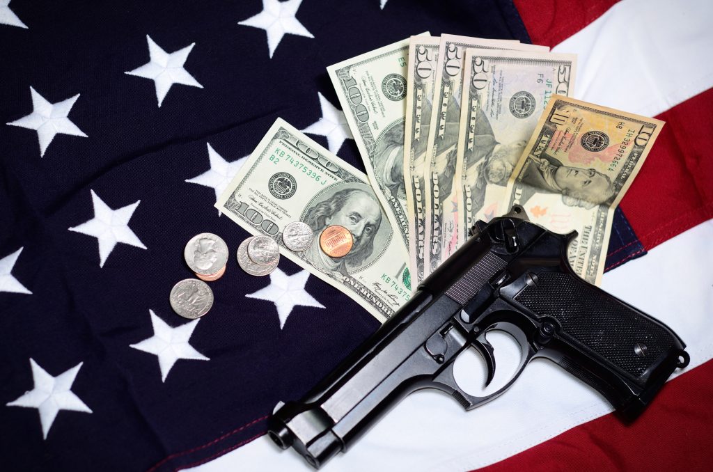 A handgun and cash laying on top of an American flag