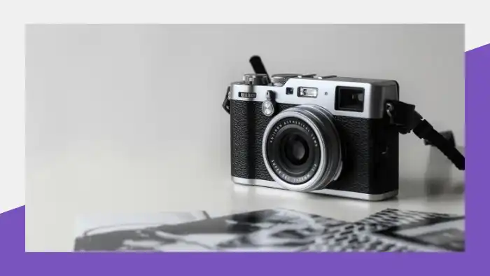 Black and gray film camera near photo prints