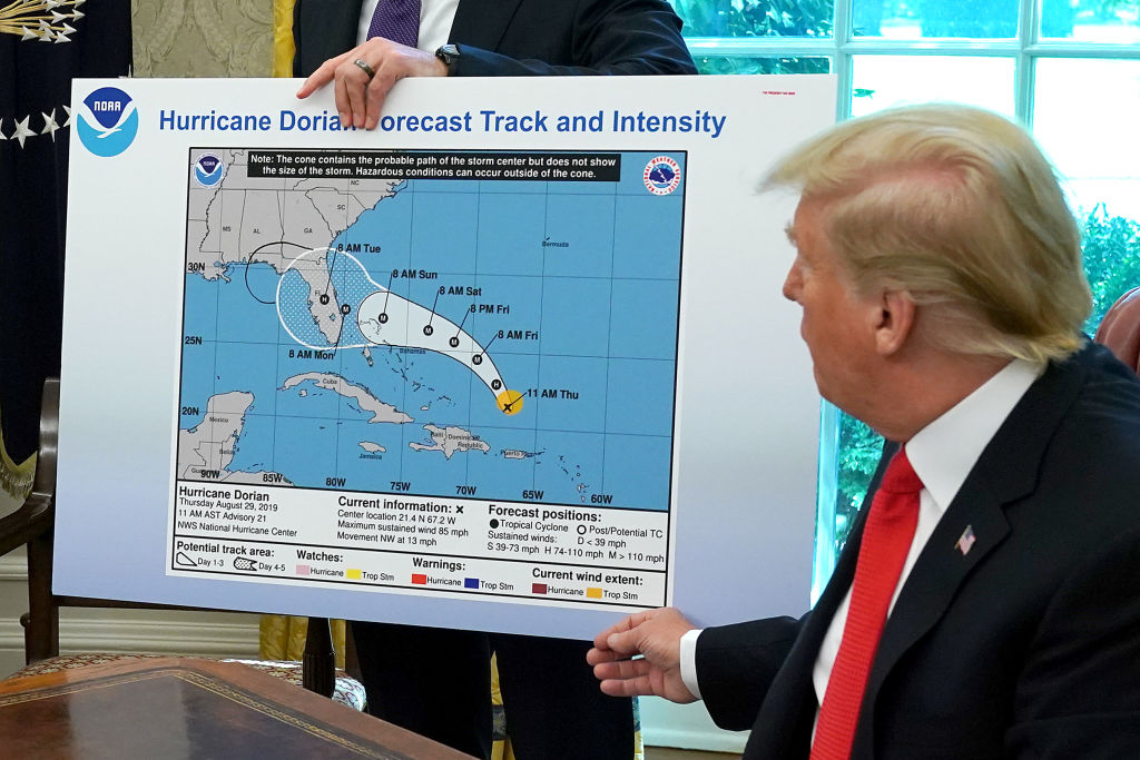 Donald trump in oval office with altered hurricane dorian projection map