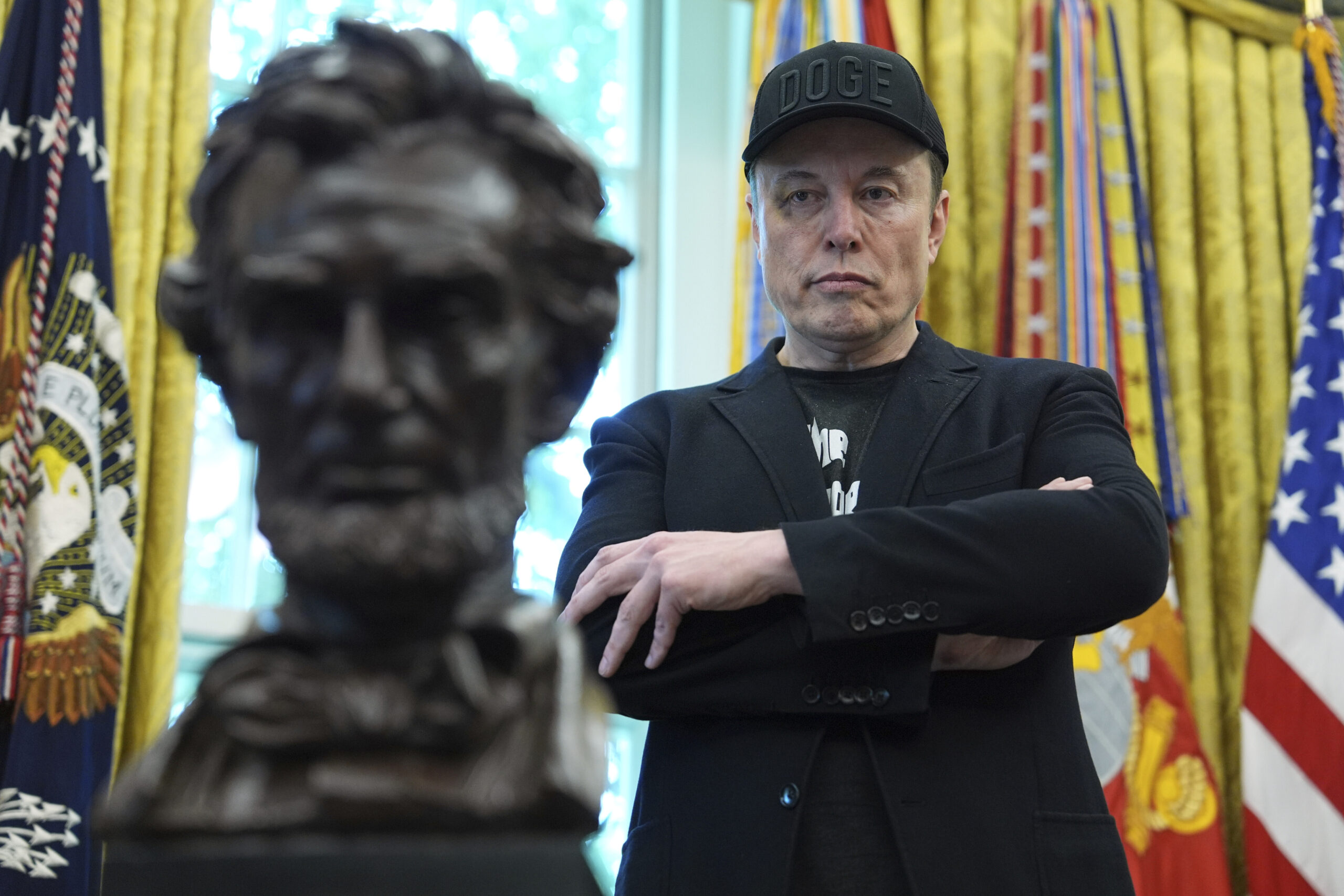 Elon musk glaring at a bust of abraham lincoln as donald trump speaks